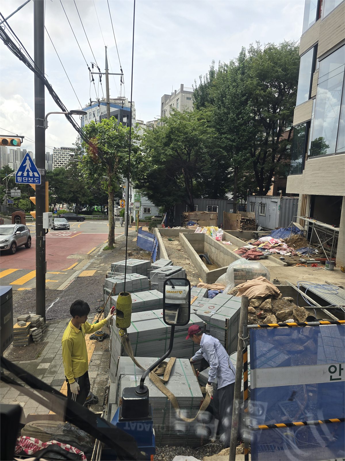 작업자들이 석재와 보도블록 묶음에 슬링을 거는 현장